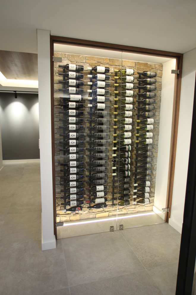 Foto på en mellanstor funkis vinkällare, med klinkergolv i porslin, vinhyllor och grått golv