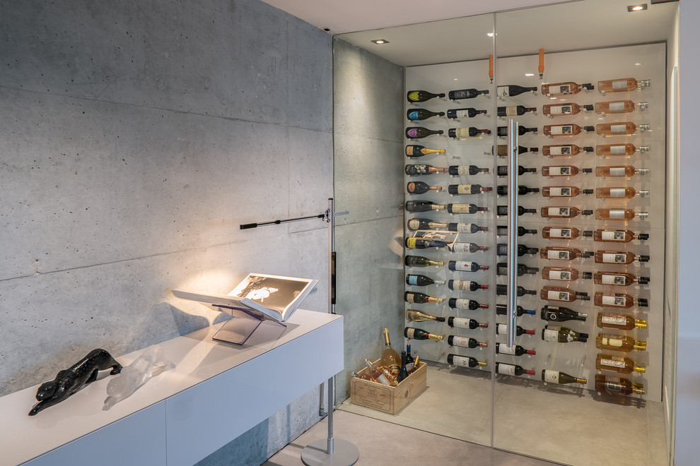 Idee per una cantina design con pavimento in cemento, portabottiglie a vista e pavimento grigio