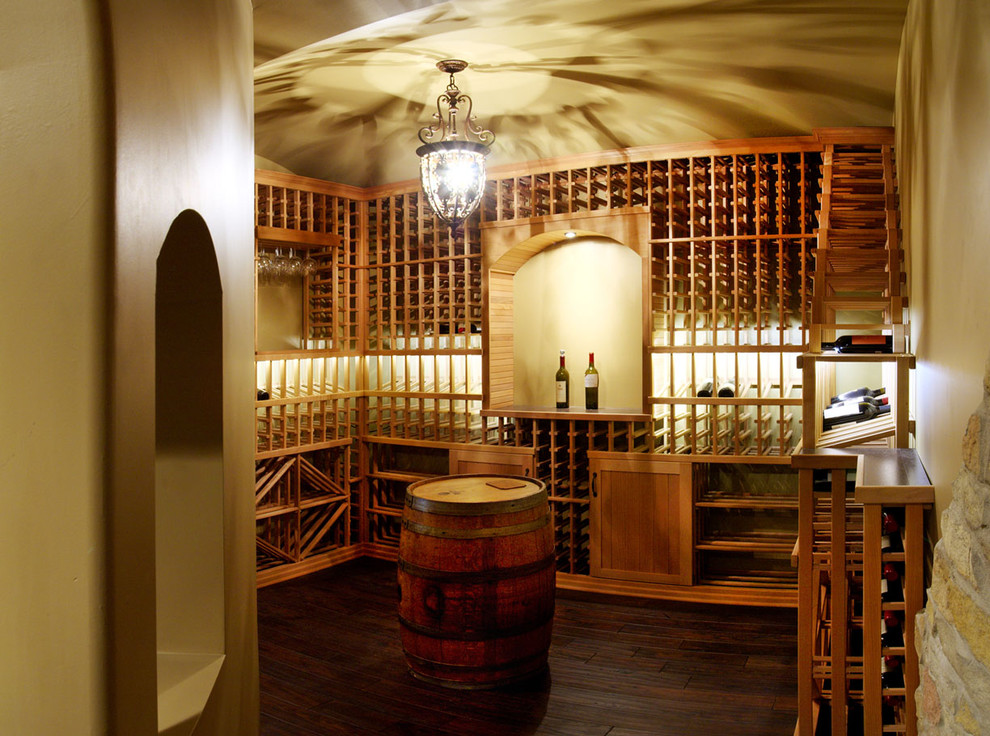 Réalisation d'une cave à vin tradition avec parquet foncé, des casiers et un sol marron.