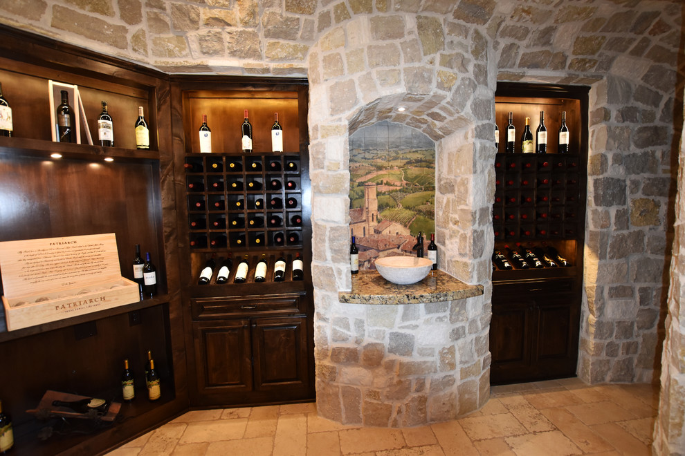 Expansive mediterranean wine cellar in Houston with travertine flooring and display racks.