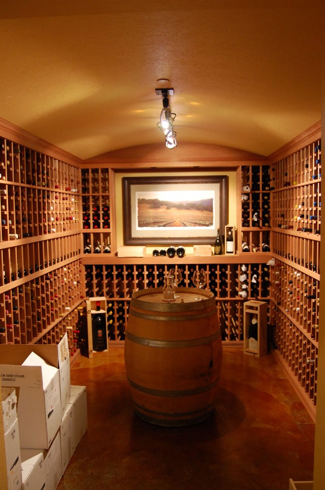 Cette photo montre une grande cave à vin chic avec sol en béton ciré, des casiers et un sol orange.