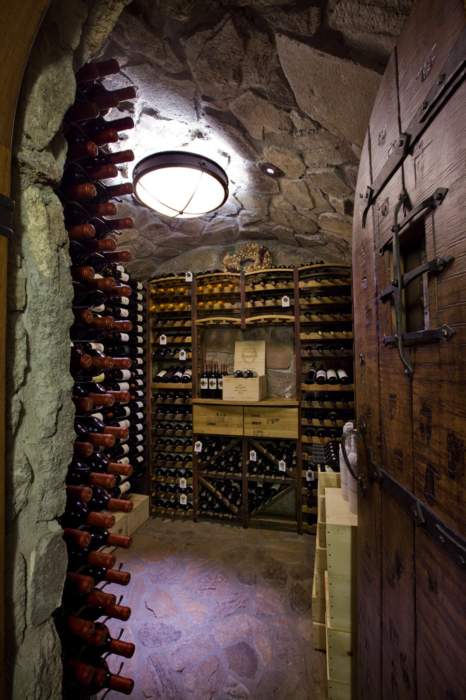 Réalisation d'une grande cave à vin chalet avec des casiers, sol en béton ciré et un sol marron.