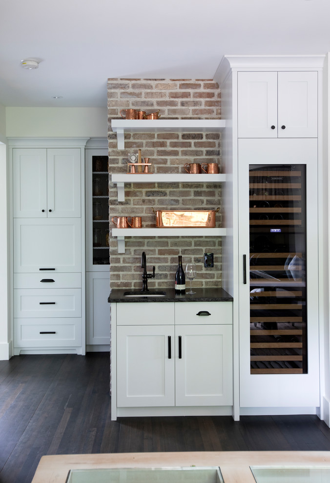 Photo of a farmhouse wine cellar in Other with dark hardwood flooring, storage racks and brown floors.