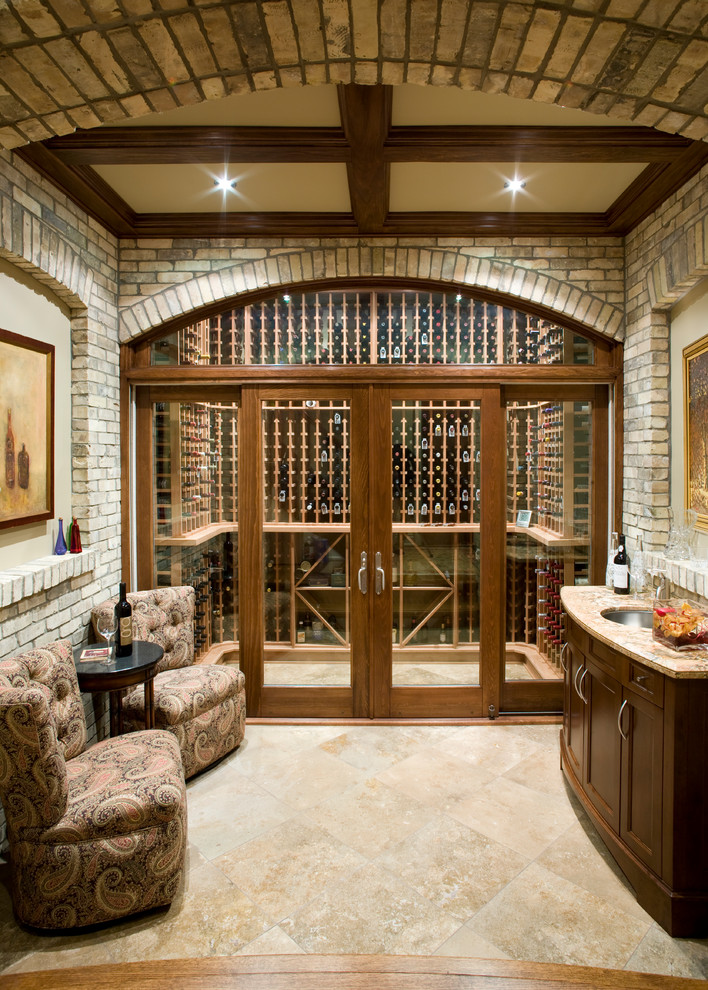Medium sized classic wine cellar in Toronto with travertine flooring and display racks.