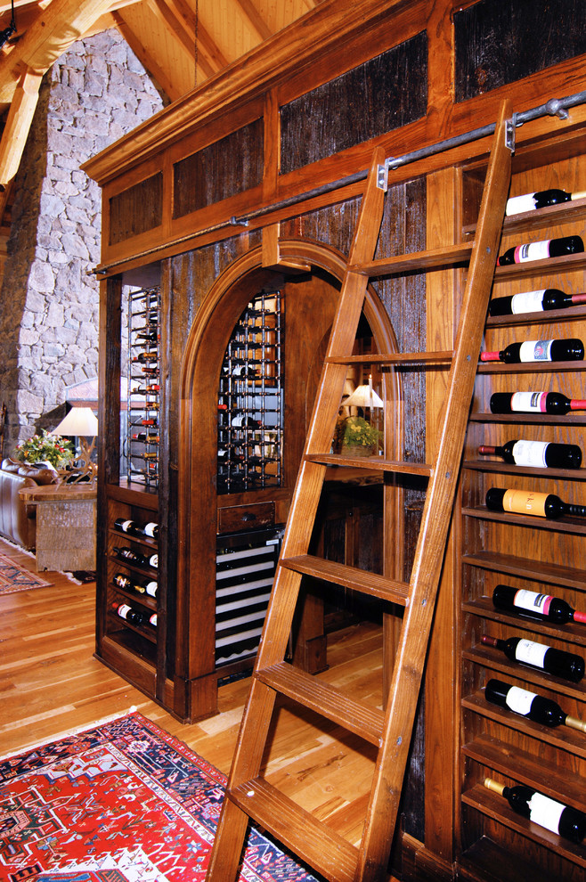 Cette photo montre une cave à vin montagne de taille moyenne avec un sol en bois brun et un présentoir.