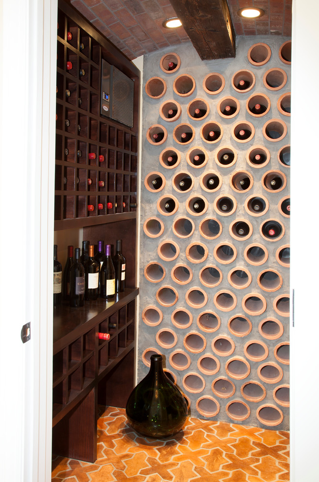This is an example of a small mediterranean wine cellar in San Francisco with terracotta flooring and display racks.