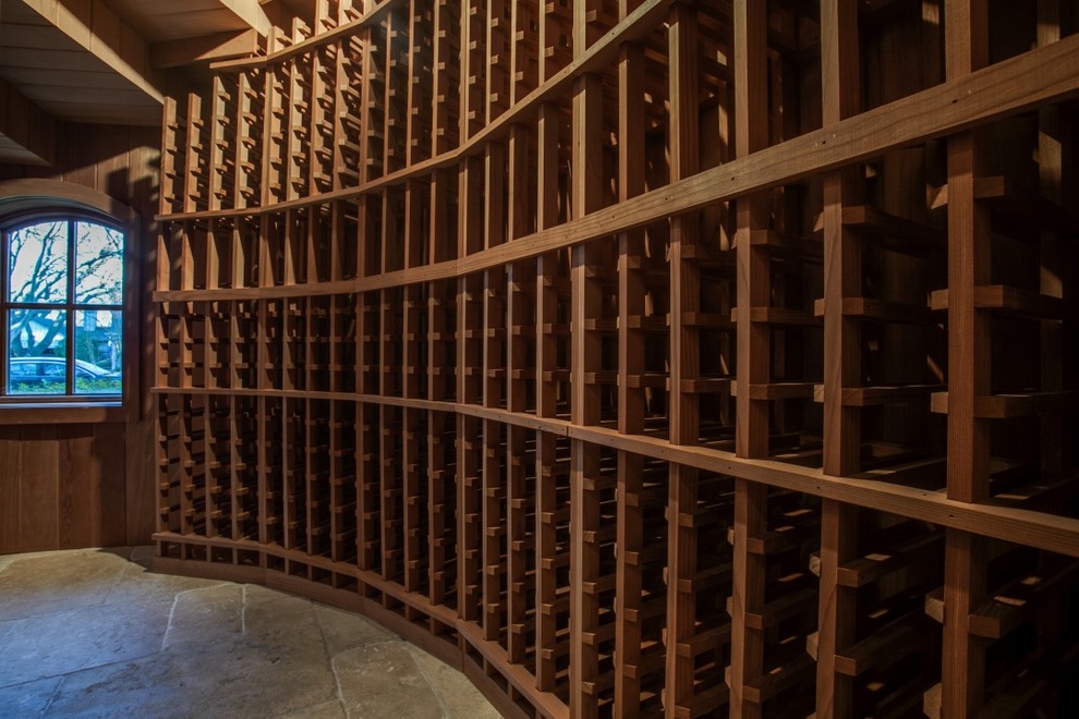 Exemple d'une cave à vin chic de taille moyenne avec un sol en travertin, des casiers et un sol beige.