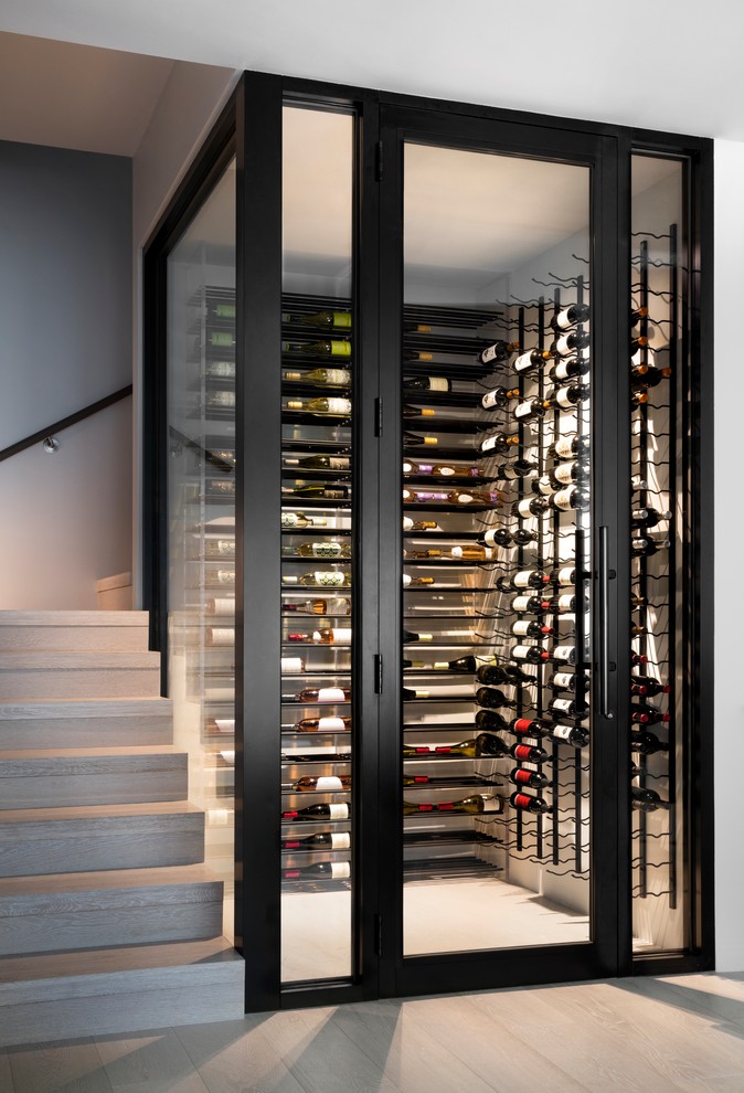 Foto de bodega contemporánea, de tamaño medio, con suelo de madera clara, botelleros y suelo marrón