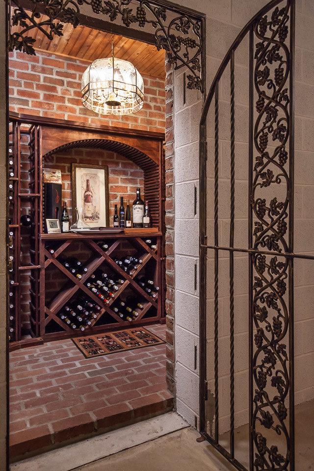 Foto på en stor vintage vinkällare, med tegelgolv, vinhyllor och rött golv
