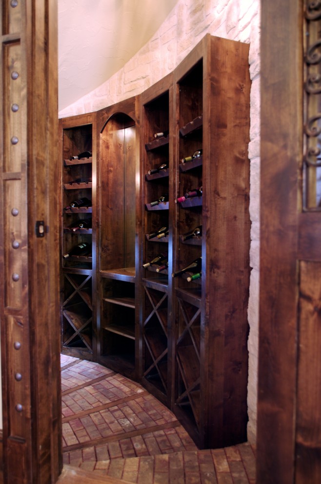 Bild på en mellanstor medelhavsstil vinkällare, med tegelgolv, vinställ med diagonal vinförvaring och rött golv
