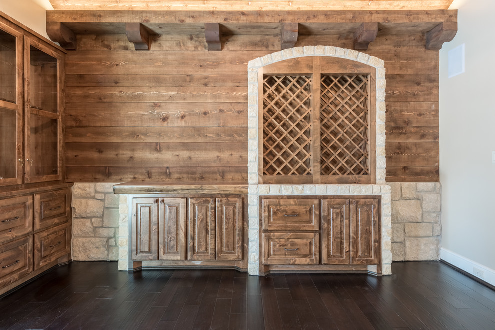 Réalisation d'une très grande cave à vin tradition avec parquet foncé, des casiers et un sol marron.