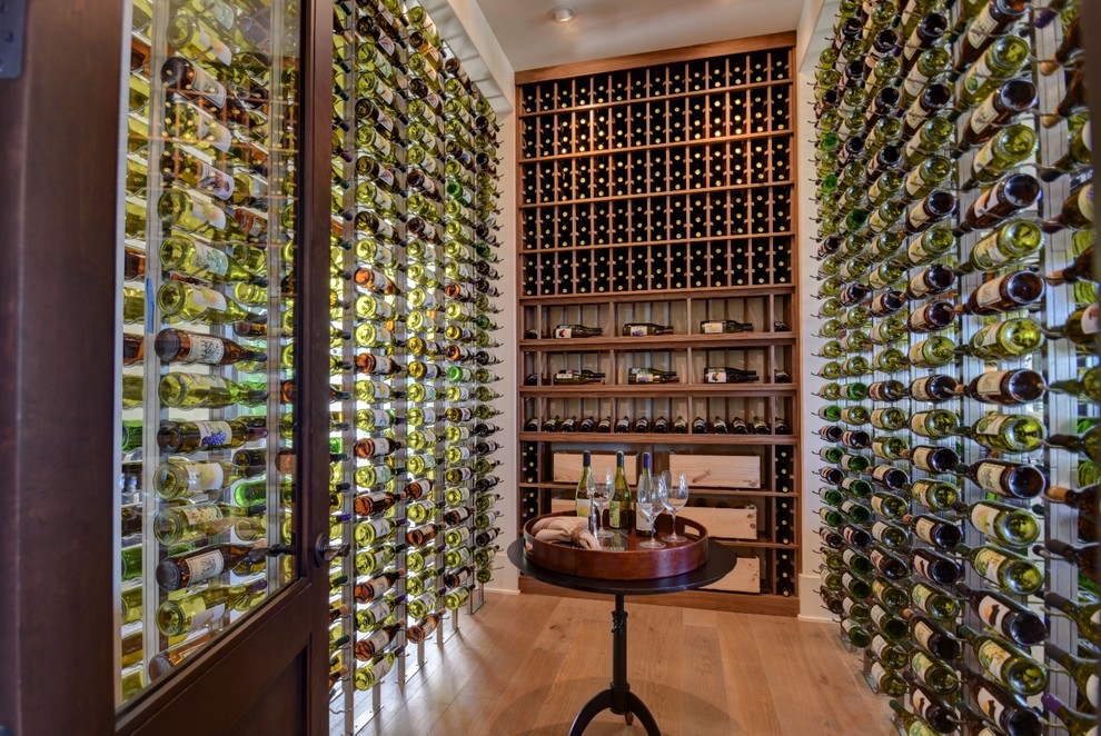 Photo of a large modern wine cellar in Los Angeles with medium hardwood flooring and display racks.