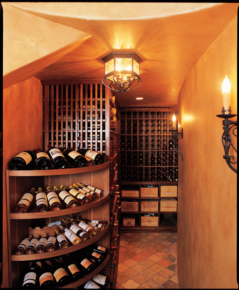 Cette image montre une grande cave à vin traditionnelle avec tomettes au sol et un présentoir.