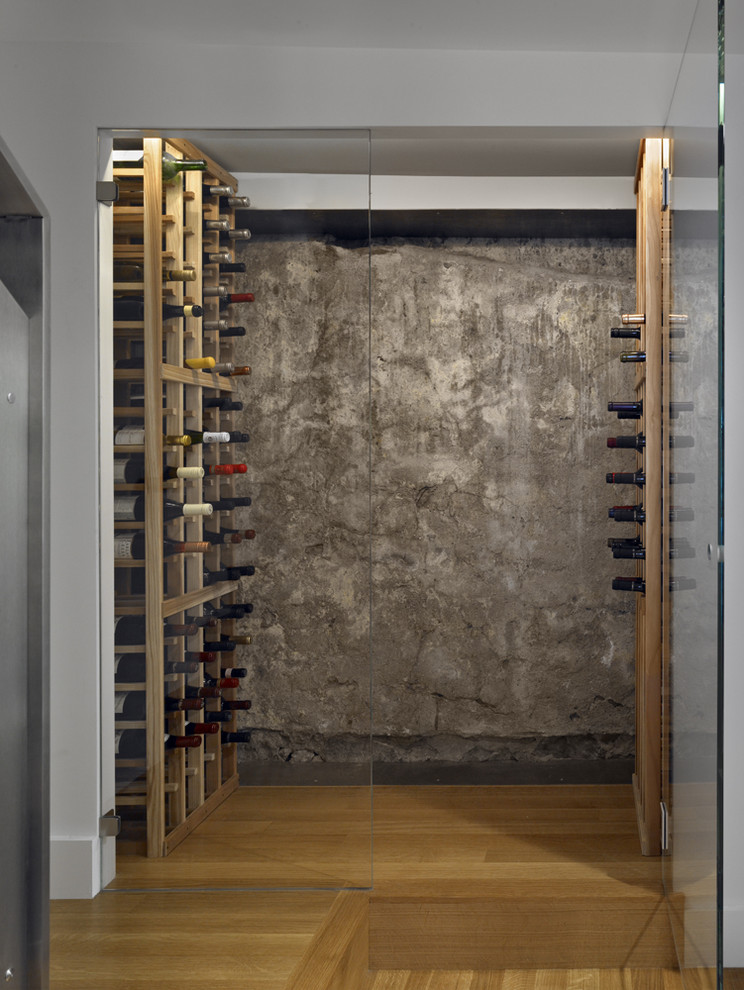 Cette photo montre une petite cave à vin moderne avec un sol en bois brun et des casiers.