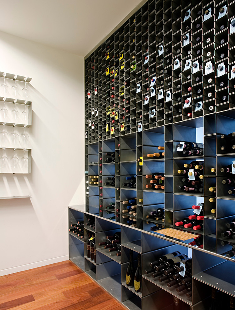 Trendy medium tone wood floor wine cellar photo in New York with storage racks