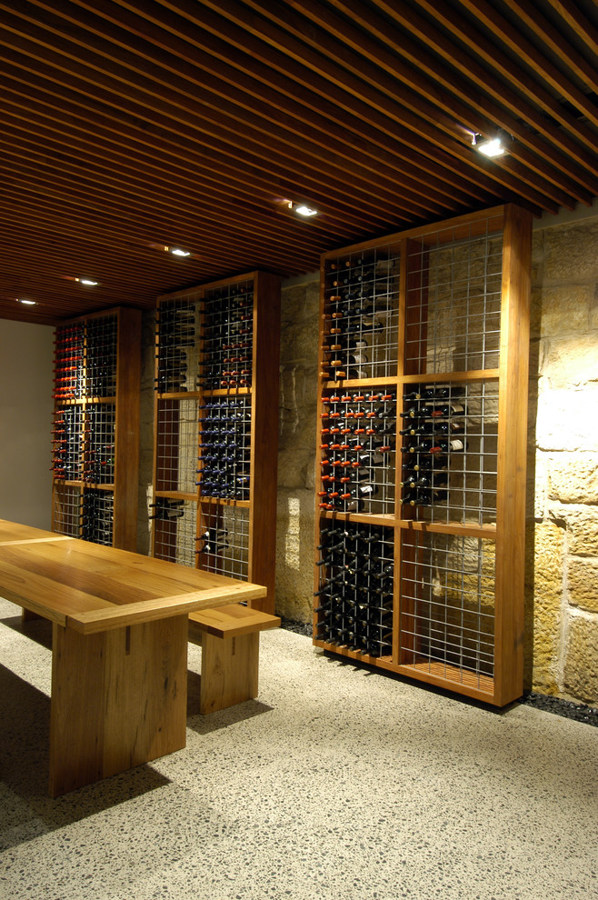 Cette image montre une grande cave à vin minimaliste avec sol en béton ciré et des casiers.