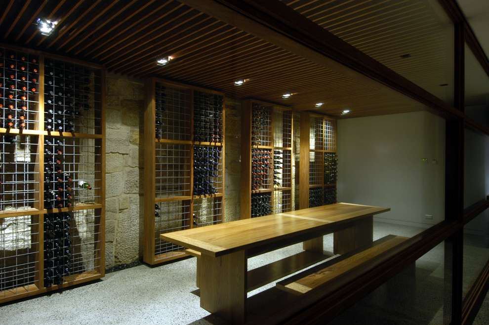 Réalisation d'une grande cave à vin minimaliste avec sol en béton ciré et des casiers.