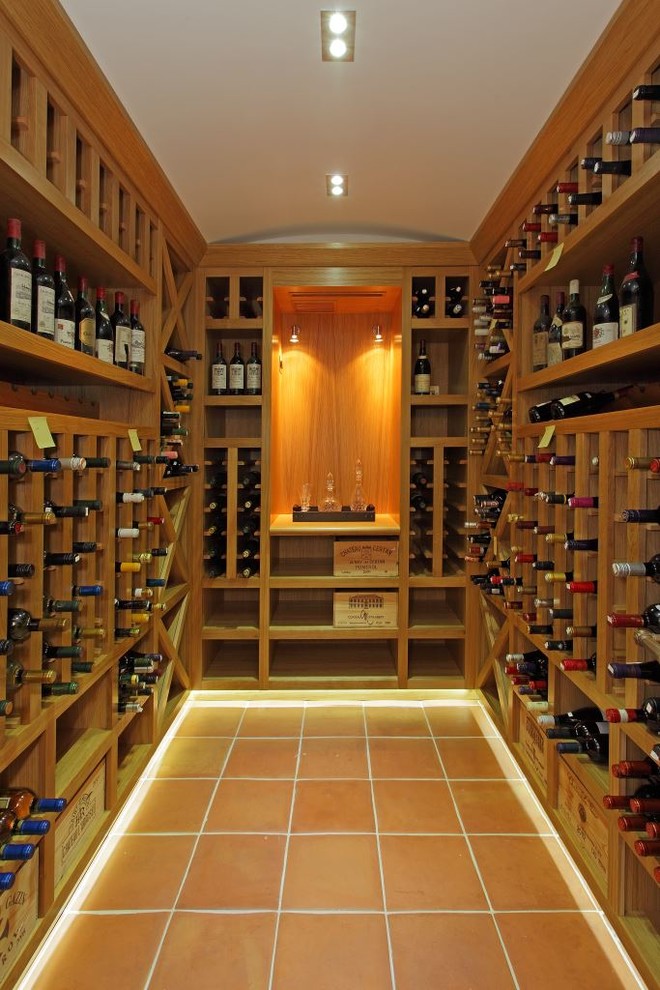 Exemple d'une cave à vin nature de taille moyenne avec tomettes au sol, des casiers losange et un sol orange.