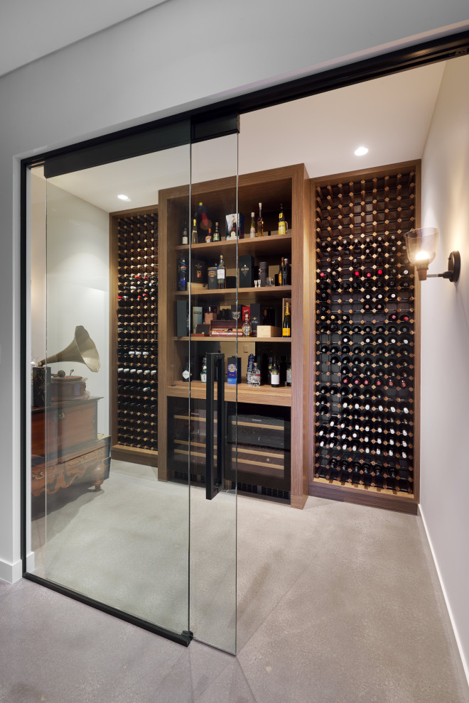 Réalisation d'une cave à vin design de taille moyenne avec des casiers et un sol marron.
