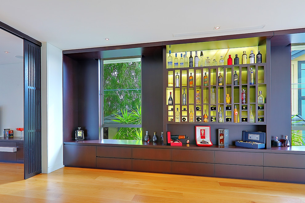 Trendy medium tone wood floor and yellow floor wine cellar photo in Sydney with display racks