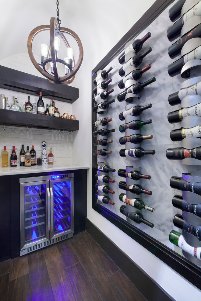 This is an example of a medium sized contemporary wine cellar in Orlando with medium hardwood flooring and display racks.