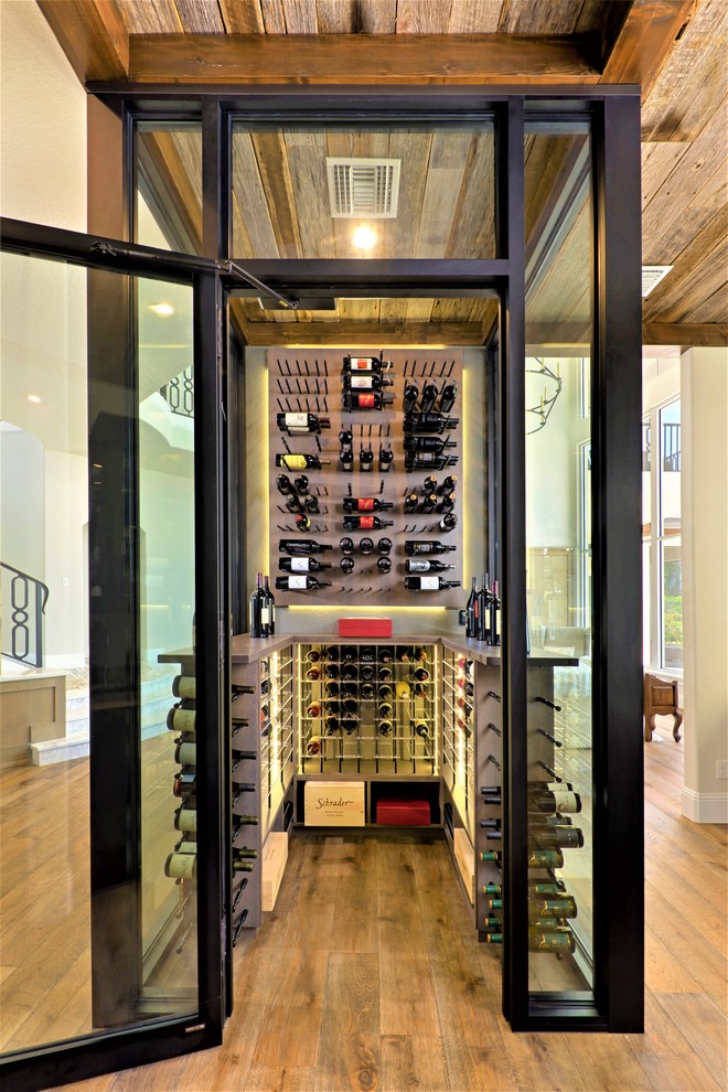 Cette photo montre une cave à vin tendance de taille moyenne avec un sol en bois brun et des casiers.