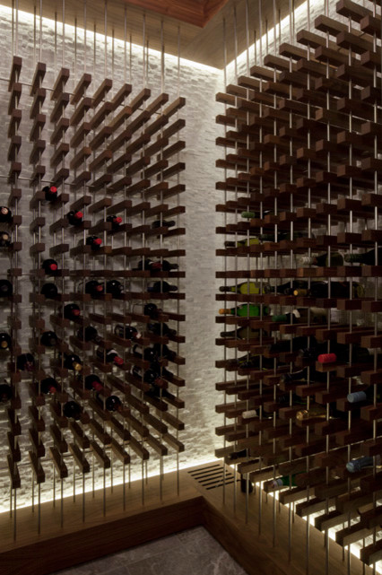 Réalisation d'une grande cave à vin minimaliste avec sol en béton ciré, des casiers et un sol gris.