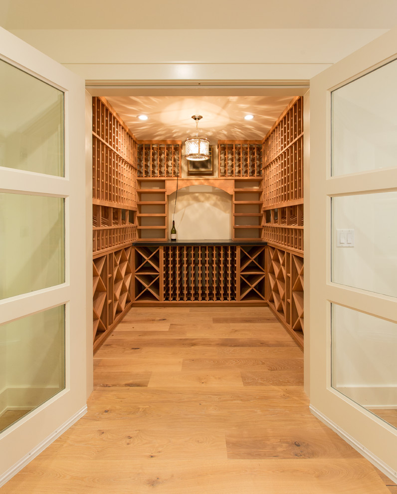 Réalisation d'une cave à vin tradition de taille moyenne avec un sol en bois brun et des casiers.