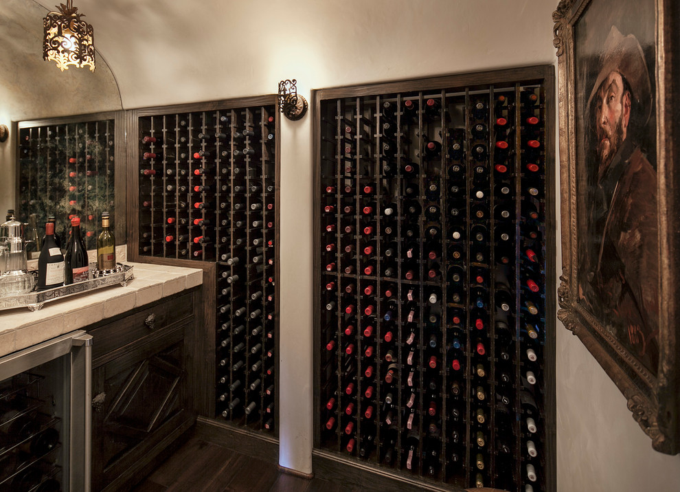 Tuscan dark wood floor wine cellar photo in Santa Barbara with diamond bins