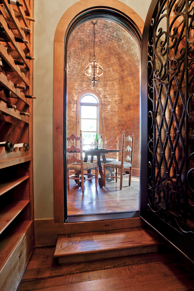Example of a mid-sized tuscan medium tone wood floor and brown floor wine cellar design in Dallas with storage racks
