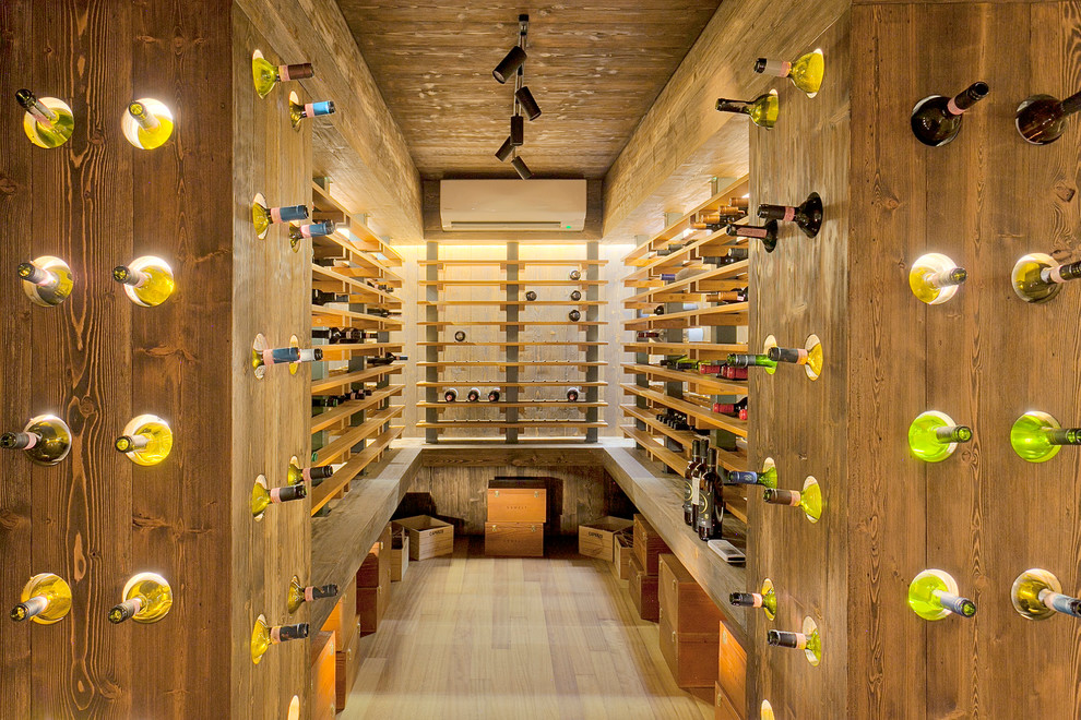Photo of a contemporary wine cellar in Other with light hardwood flooring and storage racks.