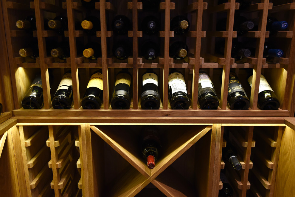 Cette photo montre une grande cave à vin tendance avec des casiers, parquet clair et un sol marron.