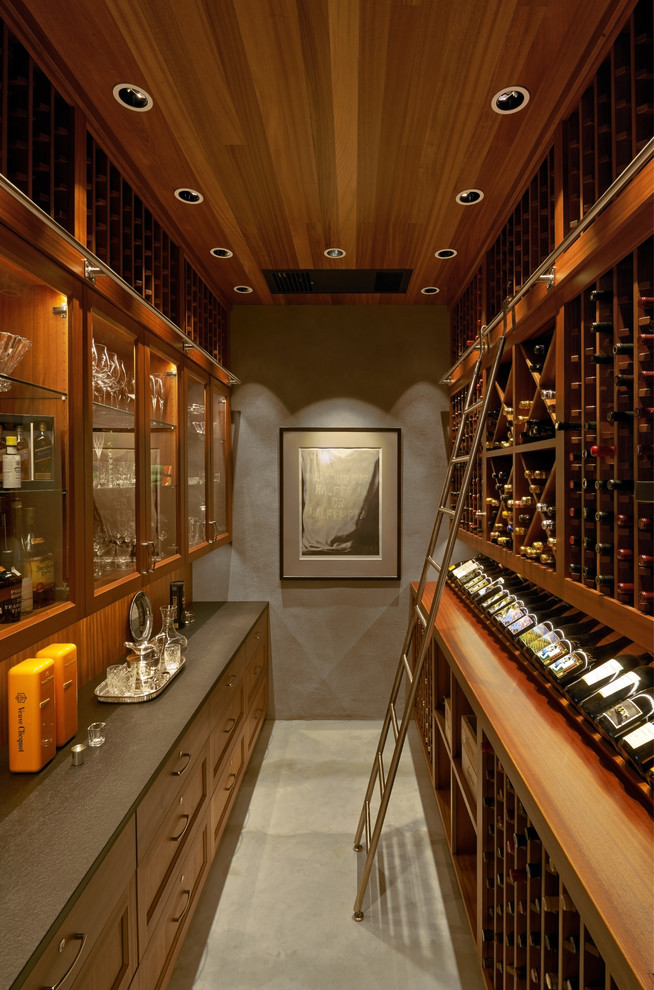 Idée de décoration pour une cave à vin design de taille moyenne avec sol en béton ciré, des casiers et un sol gris.