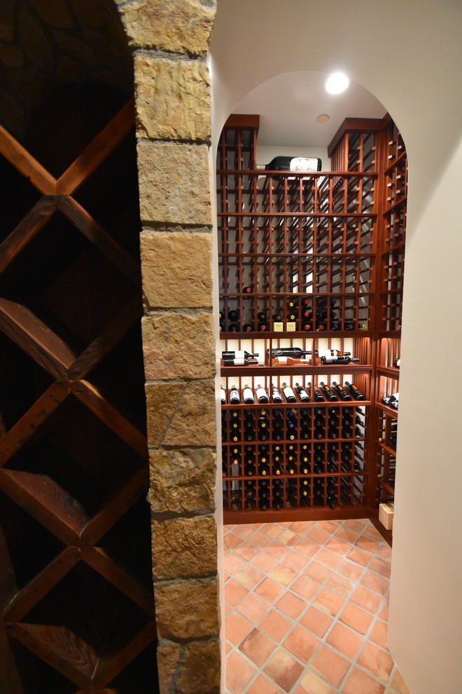 Idées déco pour une cave à vin classique de taille moyenne avec tomettes au sol, un présentoir et un sol orange.