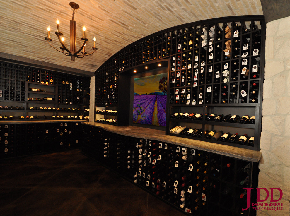 Large mediterranean wine cellar in San Diego with concrete flooring and display racks.