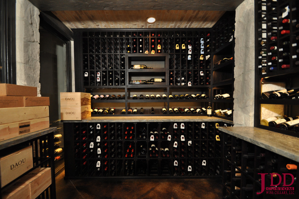 Large mediterranean wine cellar in San Diego with concrete flooring and display racks.