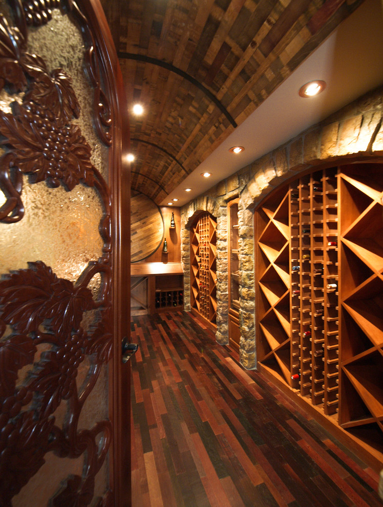 Cette photo montre une cave à vin chic de taille moyenne avec un sol en bois brun et des casiers losange.