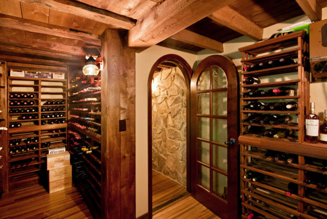Cette image montre une grande cave à vin bohème avec un sol en bois brun et des casiers.