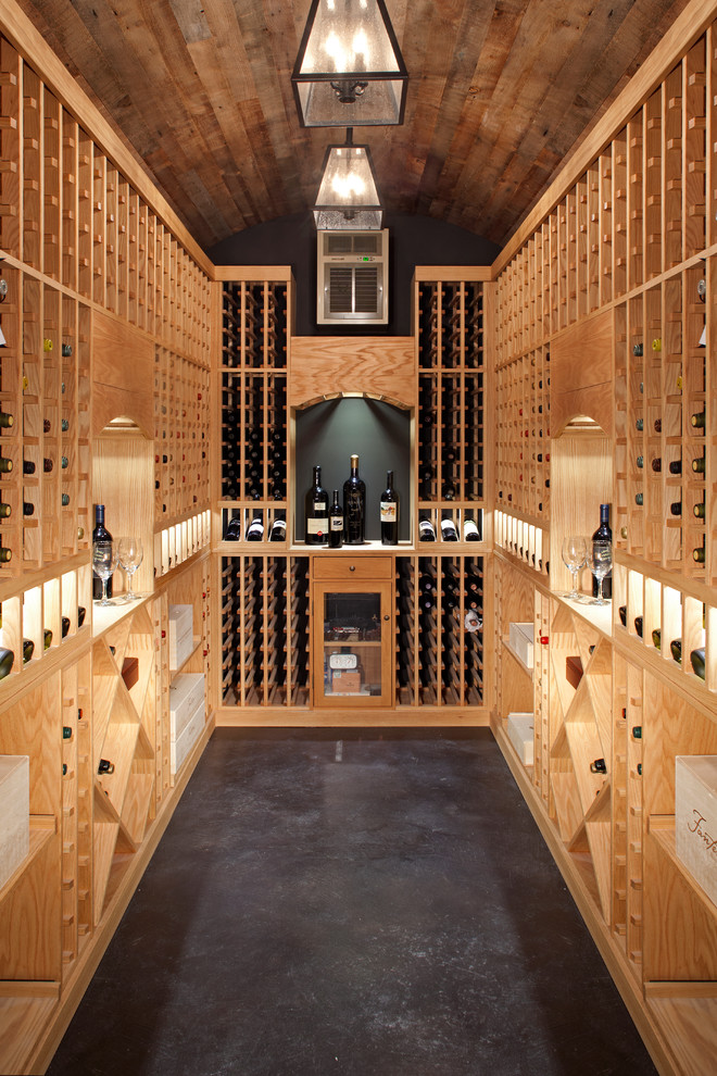 Inspiration pour une cave à vin traditionnelle de taille moyenne avec sol en béton ciré, des casiers et un sol noir.