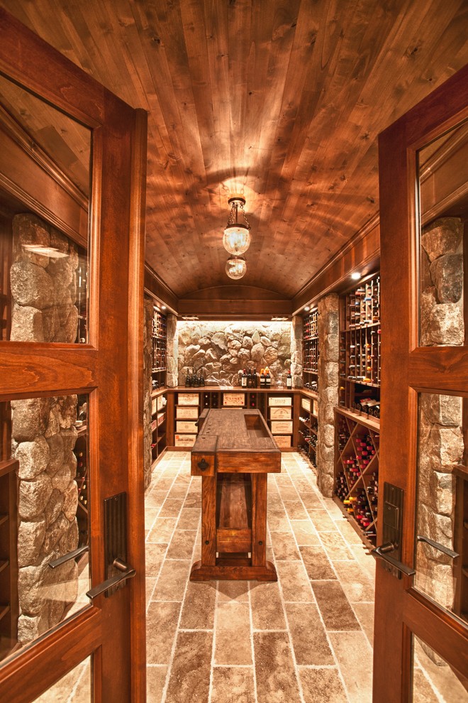 Aménagement d'une cave à vin classique avec un sol en travertin et des casiers losange.