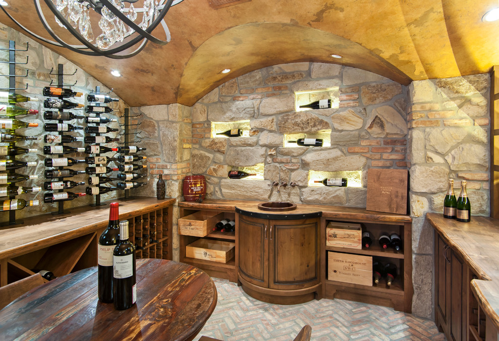 This is an example of a rustic wine cellar in Vancouver with brick flooring and display racks.