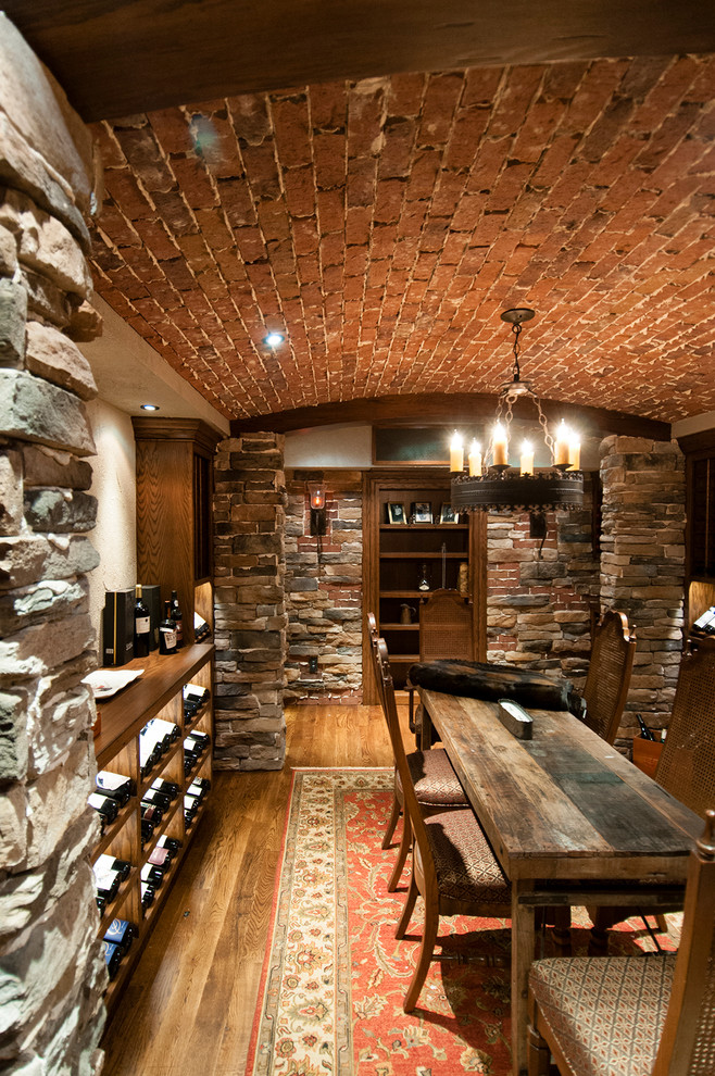 Cette photo montre une cave à vin montagne de taille moyenne avec parquet foncé et des casiers.