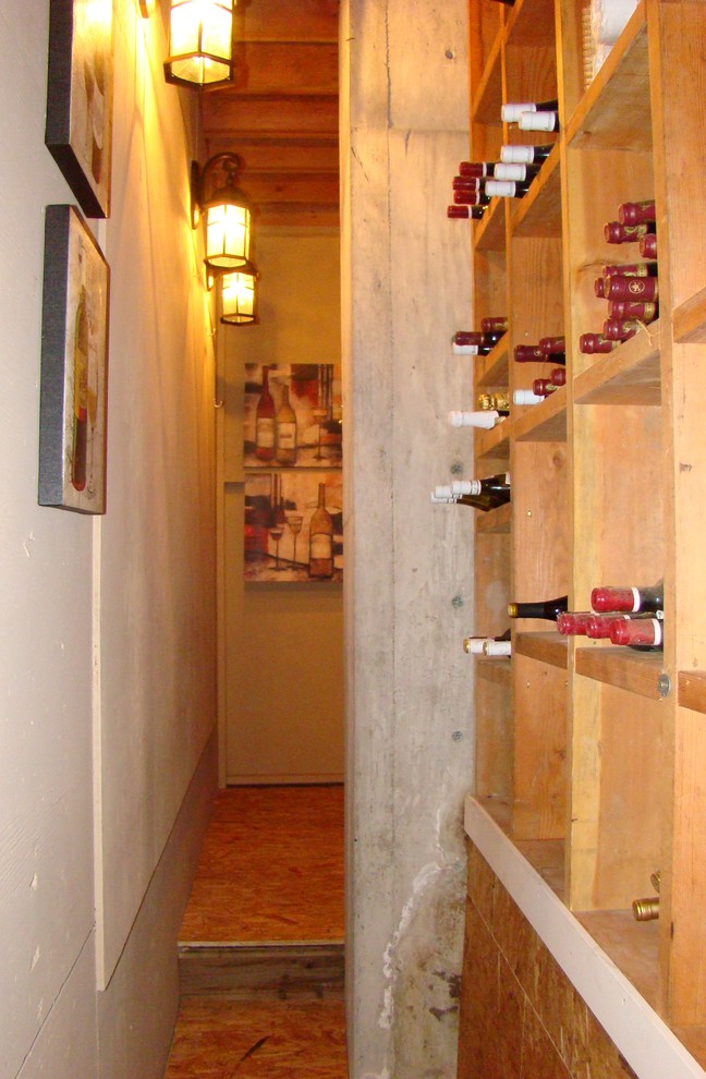 Cette photo montre une petite cave à vin méditerranéenne avec un sol en contreplaqué, un présentoir et un sol marron.