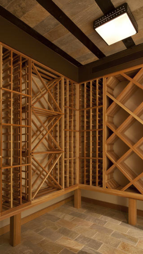 Cette photo montre une cave à vin chic de taille moyenne avec un sol en travertin, des casiers losange et un sol beige.