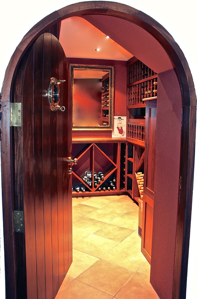 Klassisk inredning av en mellanstor vinkällare, med travertin golv och vinhyllor