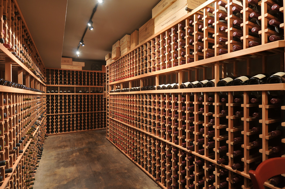 Bild på en stor vintage vinkällare, med mellanmörkt trägolv, vinhyllor och brunt golv