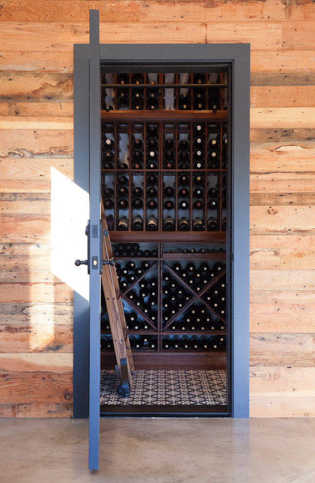 Cette photo montre une petite cave à vin industrielle avec sol en béton ciré et des casiers.