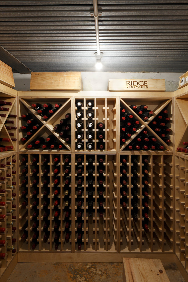 Cette image montre une grande cave à vin design avec sol en béton ciré, des casiers et un sol gris.