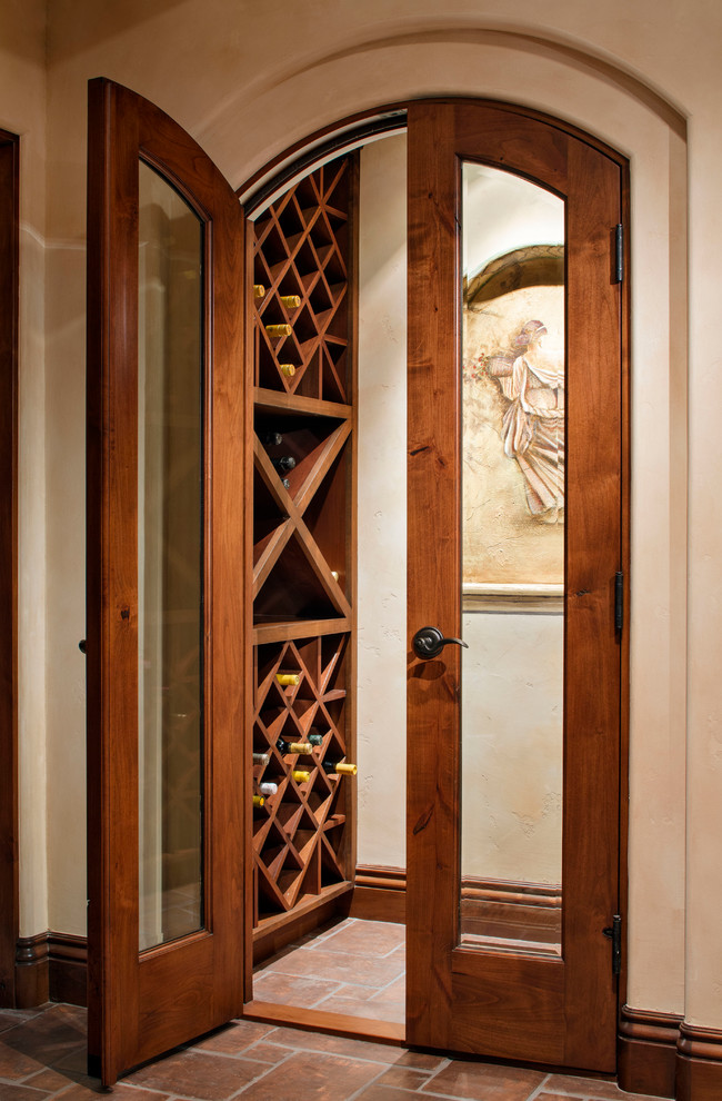 Photo of a small mediterranean wine cellar in San Diego with terracotta flooring, storage racks and brown floors.