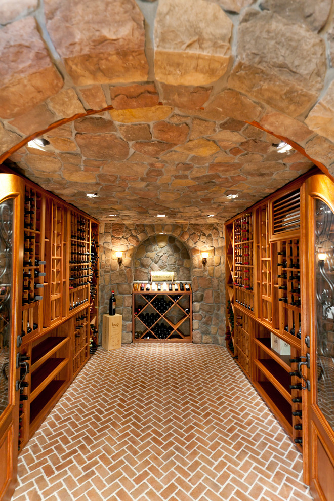 Exemple d'une grande cave à vin chic avec un sol en brique, des casiers et un sol rouge.